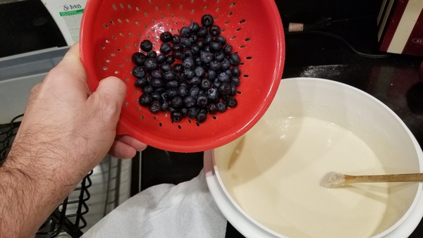 Waffle batter in bowl. Blueberries in colander.